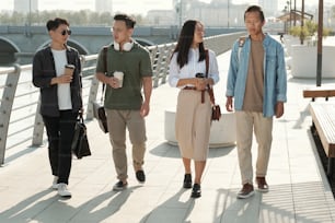 Grupo de empresários de etnia asiática que se deslocam ao longo da margem do rio em dia ensolarado