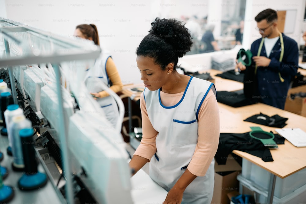 African American seamstress working at embroidery machine in a textile factory.