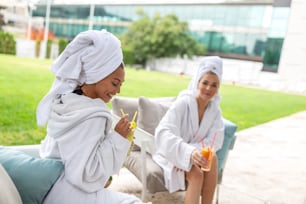 Happy young beautiful women enjoying fun time after spa procedures together in luxury hotel, wearing towels on heads and bathrobes.