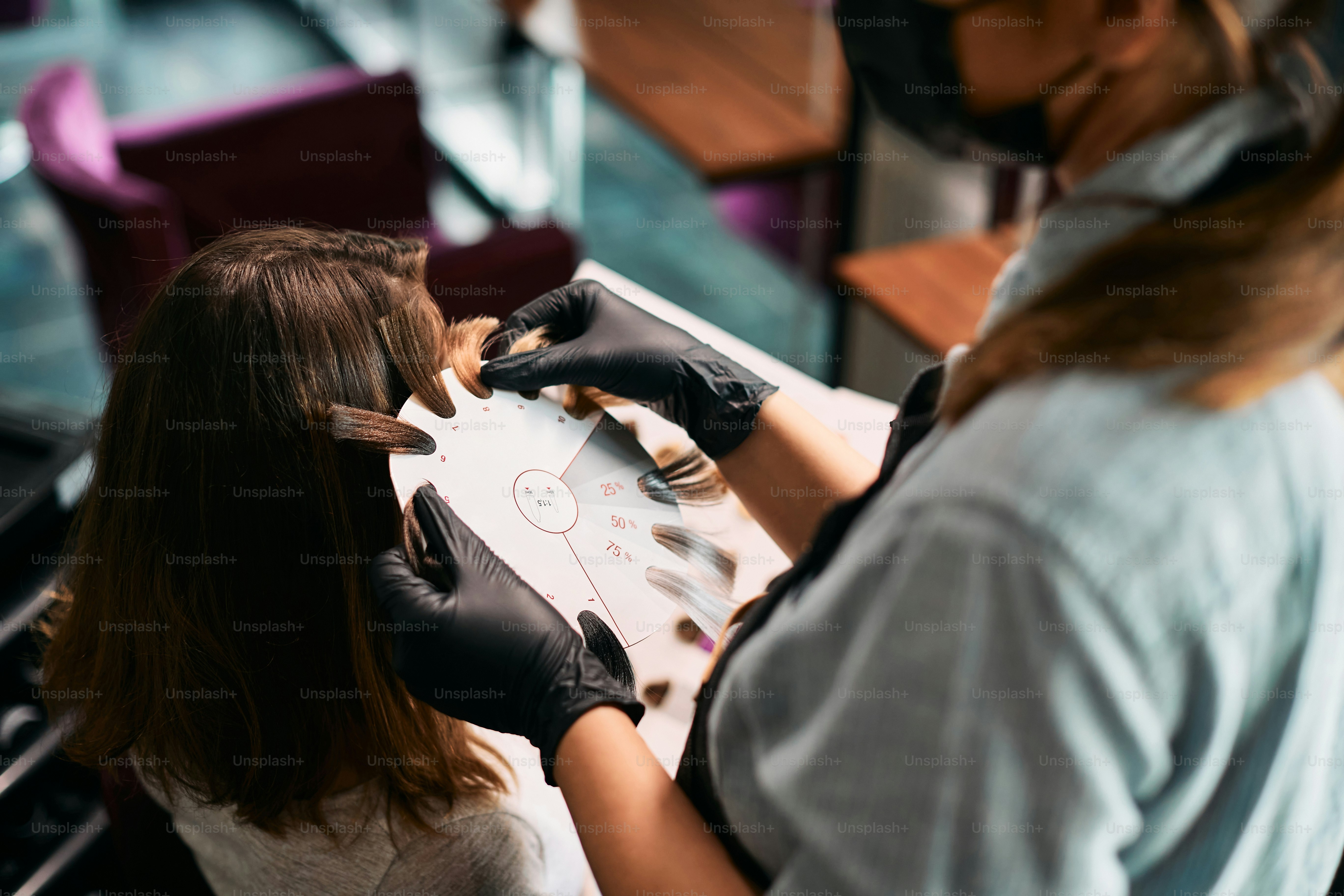 Gros plan d’une coiffeuse choisissant la couleur des cheveux pour sa cliente dans un salon.