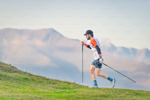 Athlete practicing Nordic walking on hilly meadows