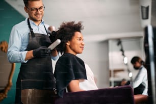 Smiling black woman enjoying while getting hair treatment at hairdresser's.