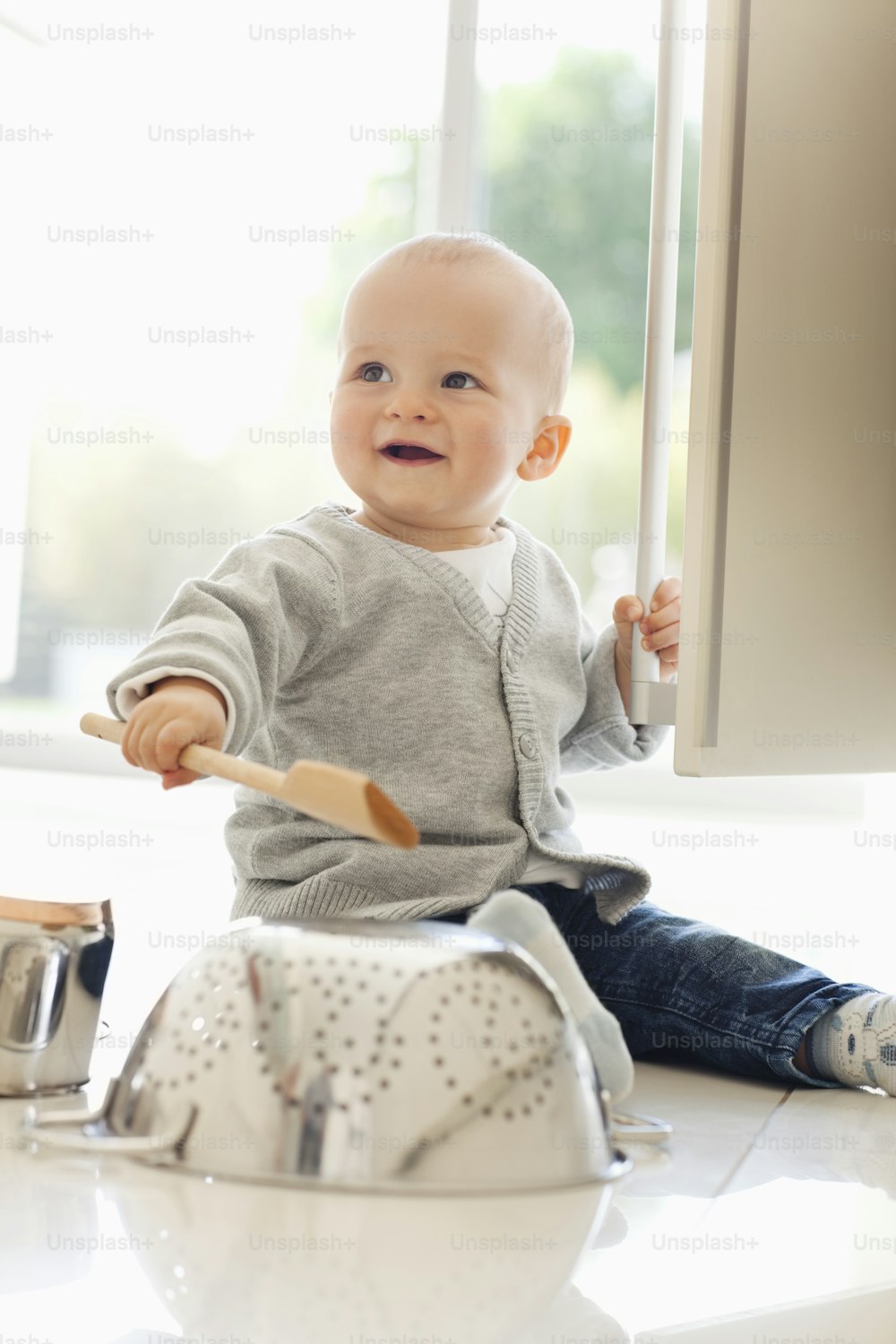 a baby sitting on a counter with a wooden spoon