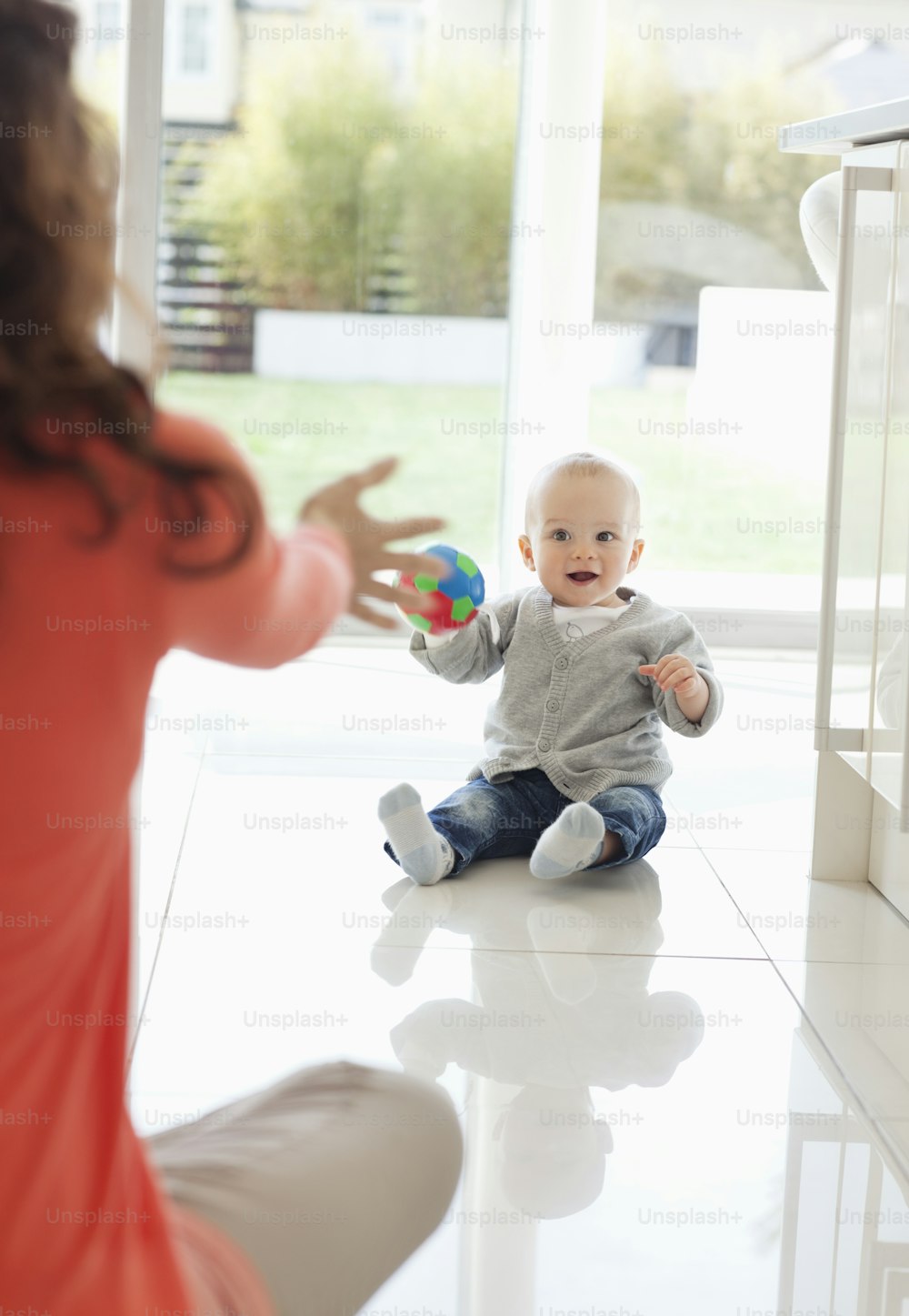 um bebê sentado no chão brincando com uma bola