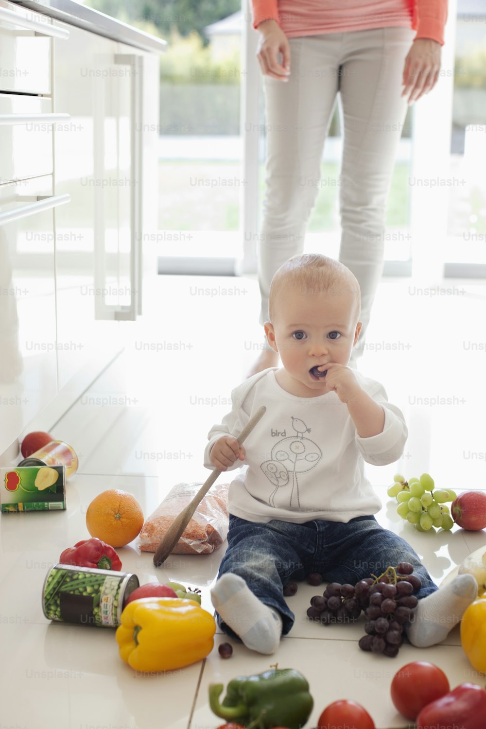果物や野菜に囲まれた床に座っている赤ちゃん