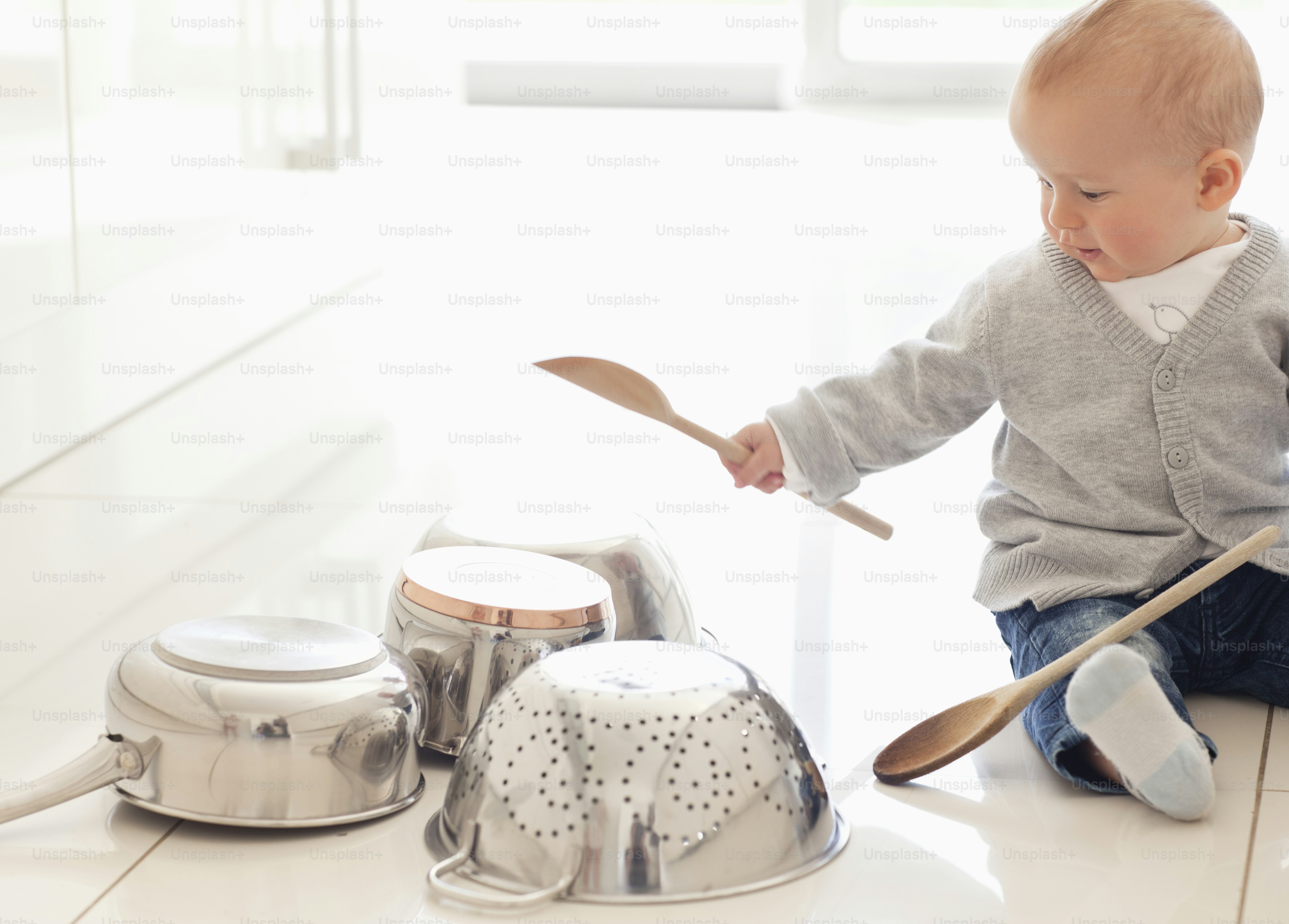 a baby sitting on the floor playing with a spoon
