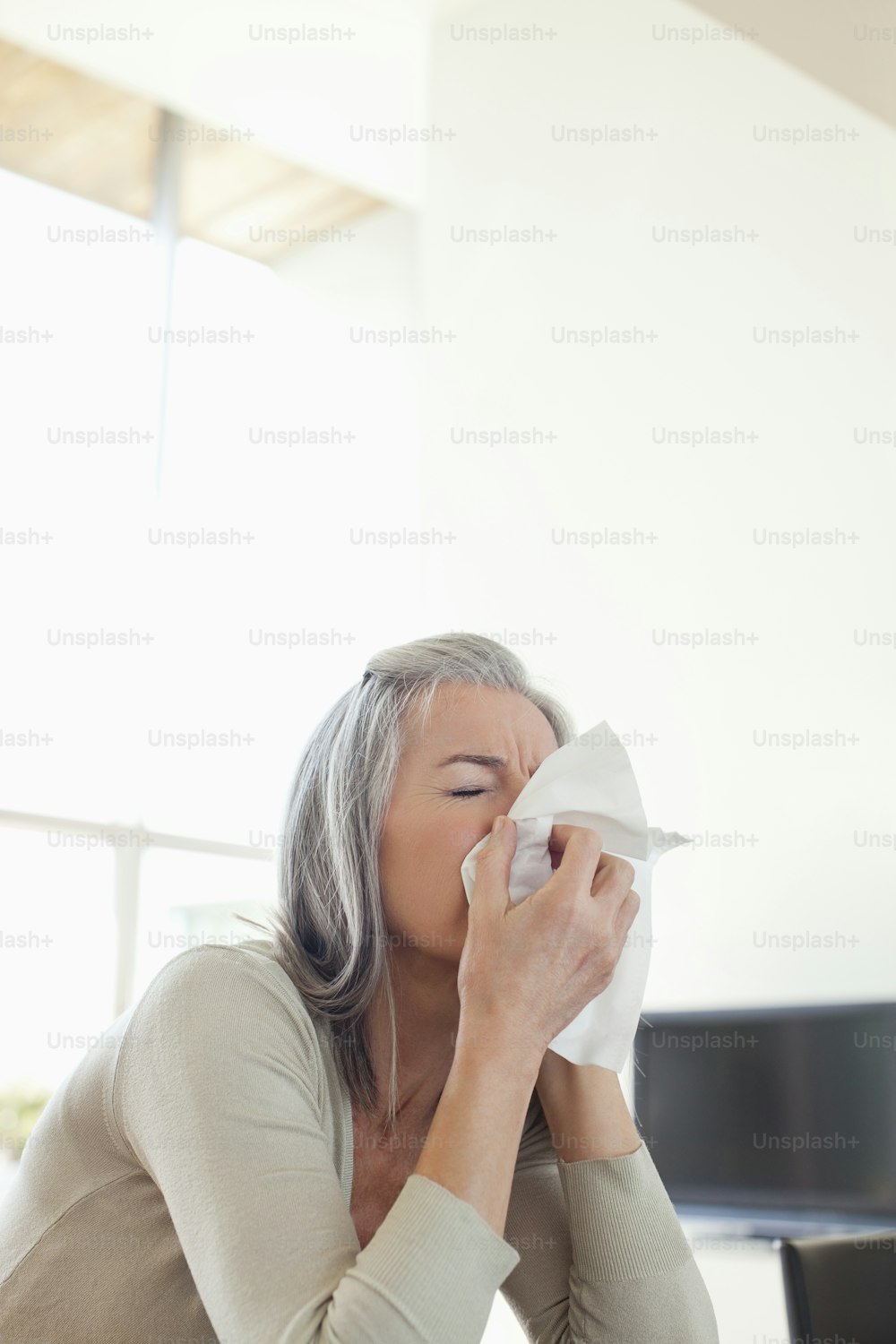 a woman sitting on a couch blowing her nose