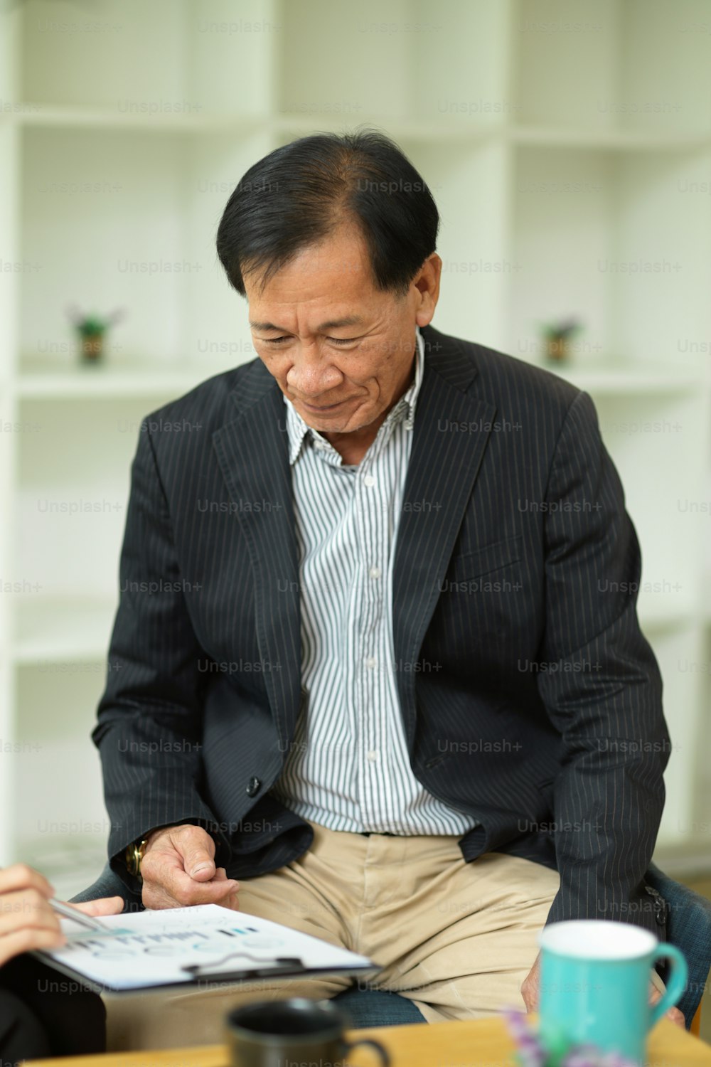 Ritratto di uomo d'affari asiatico di mezza età di successo che legge un documento di contratto commerciale nel suo ufficio.