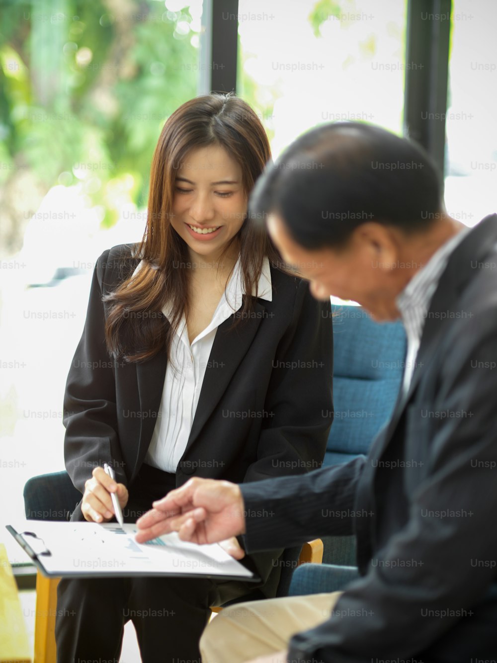 Cheerful young businesswoman working together with a professional aged businessman in meeting room.
