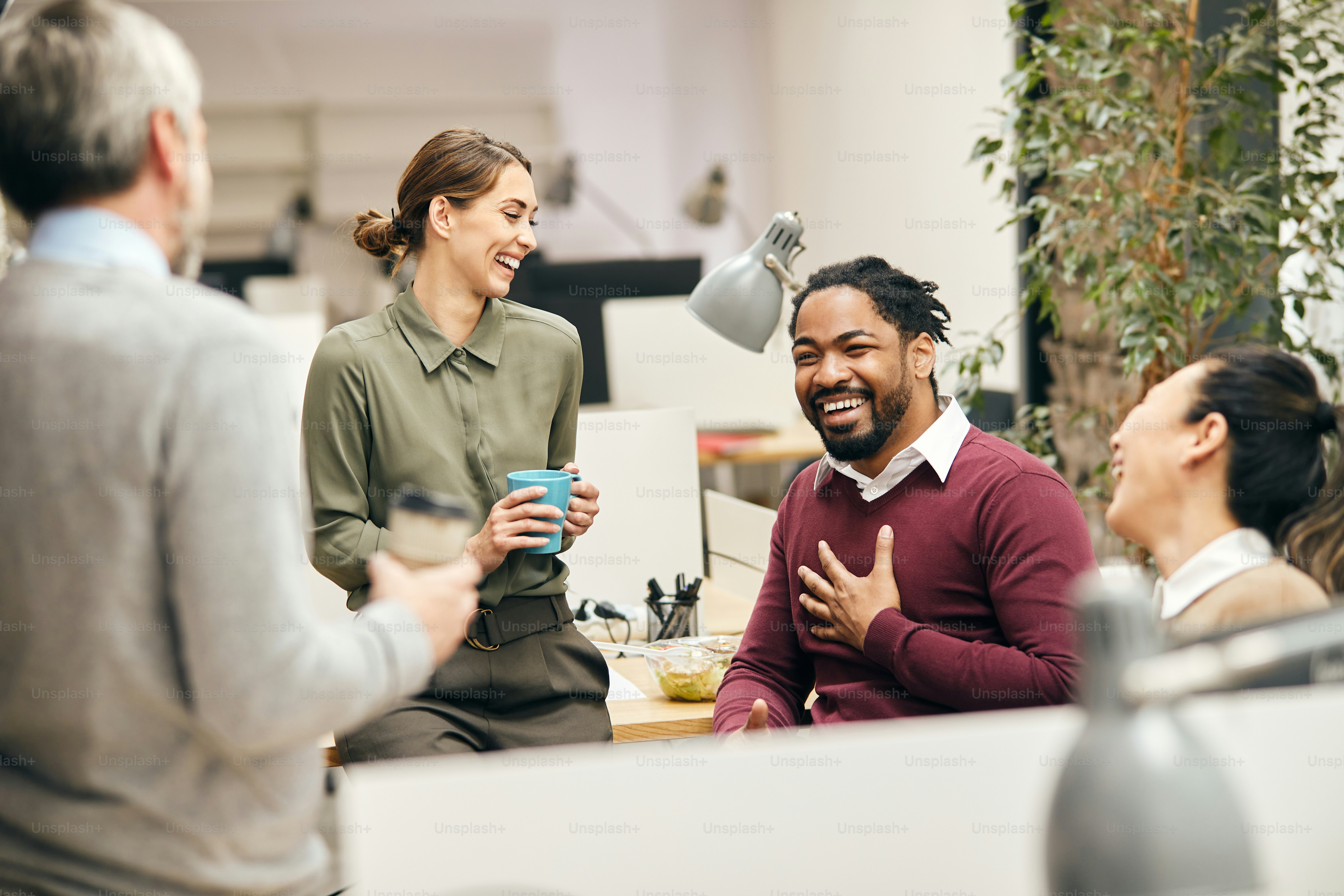 Multi-ethnic group of entrepreneurs laughing while talking to each other on a break in the office