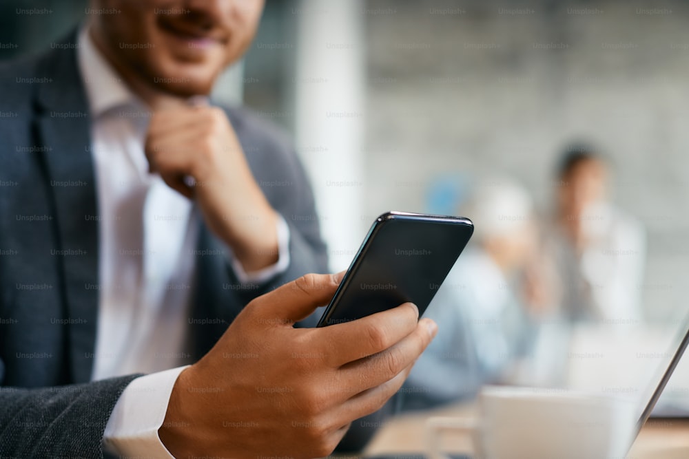 Close-up de mensagens de texto do empreendedor no celular durante a reunião de negócios no escritório.
