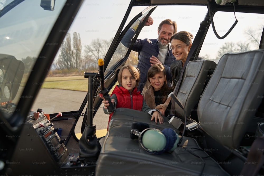 Des parents et des enfants excités jetant un coup d’œil dans le cockpit d’un hélicoptère tout en se préparant à voler
