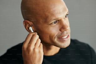 Young African American man using wireless in-ear headphones while listening music.