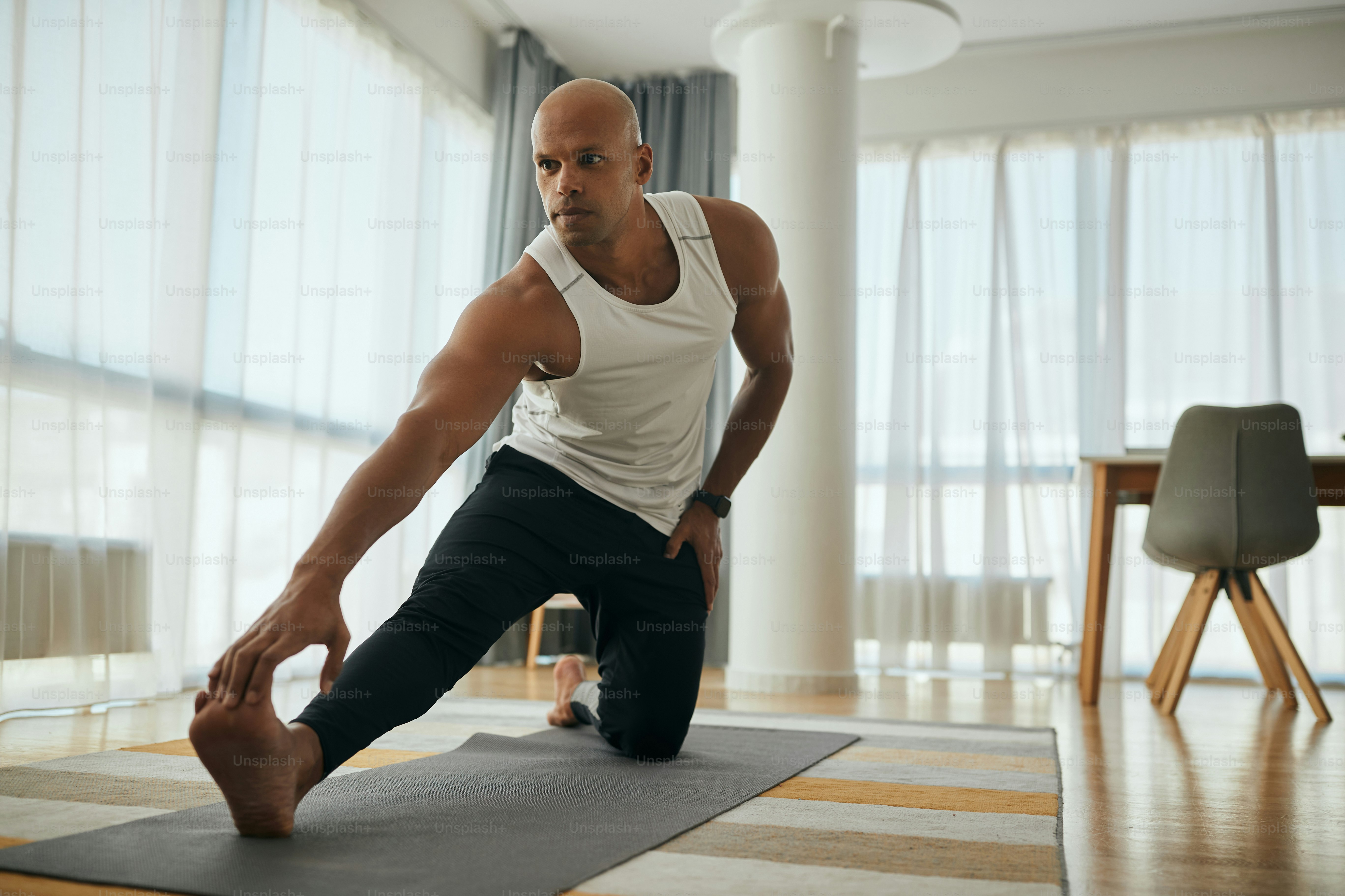 Young black athlete doing stretching exercises while working on at home.