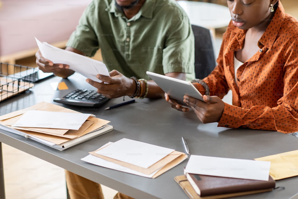 Close-up of African American couple sitting at table with bills and letters and analyzing month costs