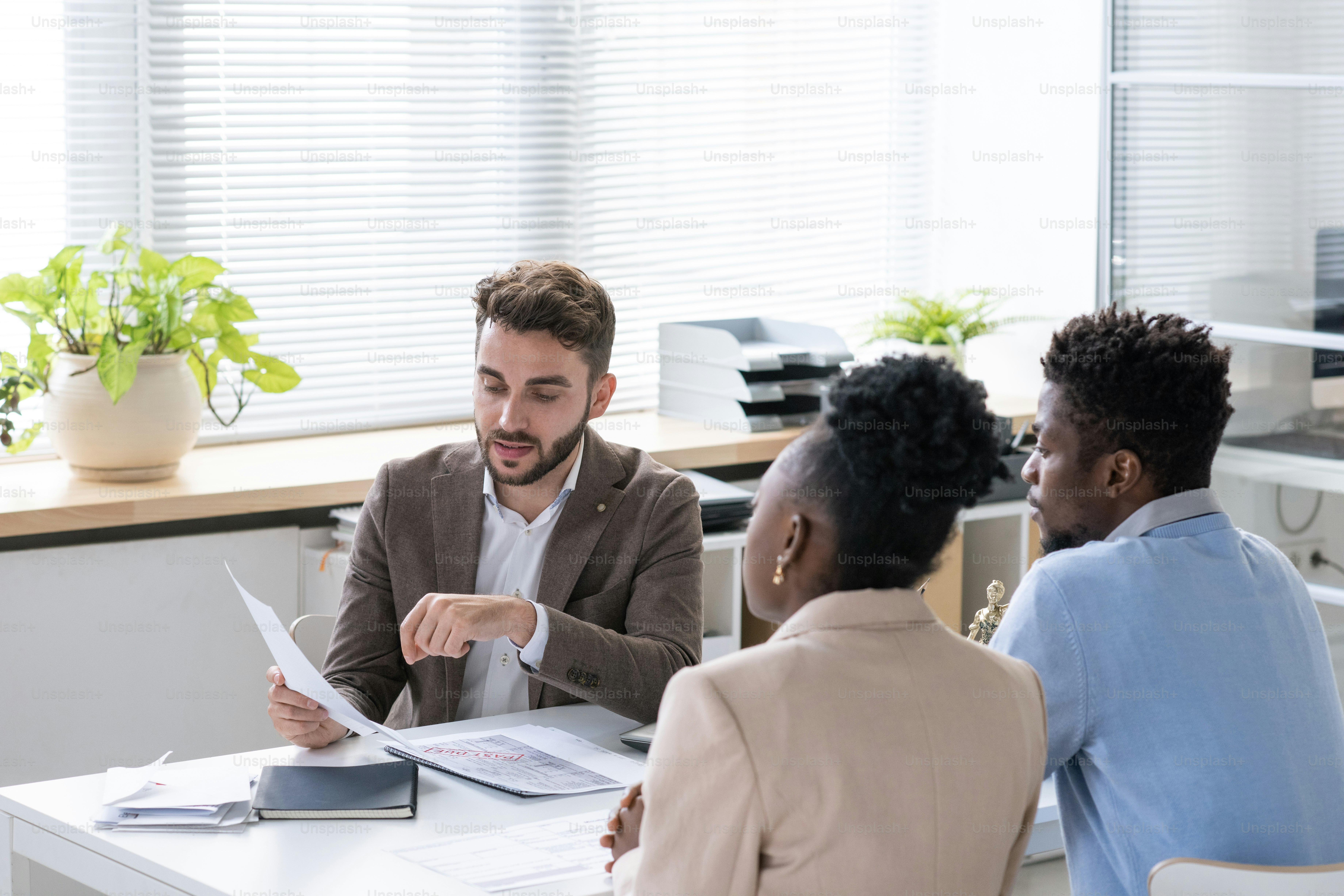 Lawyer consulting with clients over contract documents in an office