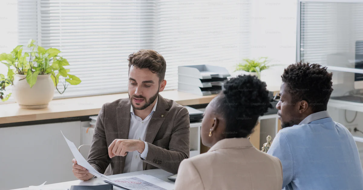 Lawyer consulting with clients over contract documents in an office