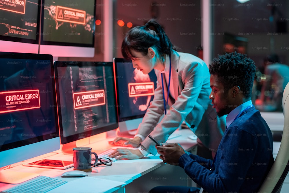 화면에 심각한 오류가 있는 컴퓨터 앞에서 기술적인 문제를 해결하려는 두 명의 젊은 이문화 프로그래머