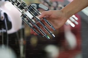 여성의 손은 사이보그의 금속 손을 클로즈업합니다. 철강 로봇 구조, 공정 자동화, 미래 장비