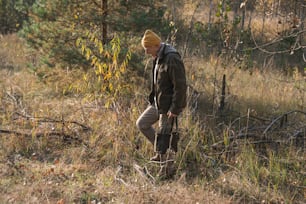 Full length view of the senior man walking through the forest and picking mushrooms during the sunny autumn day. Stock photo