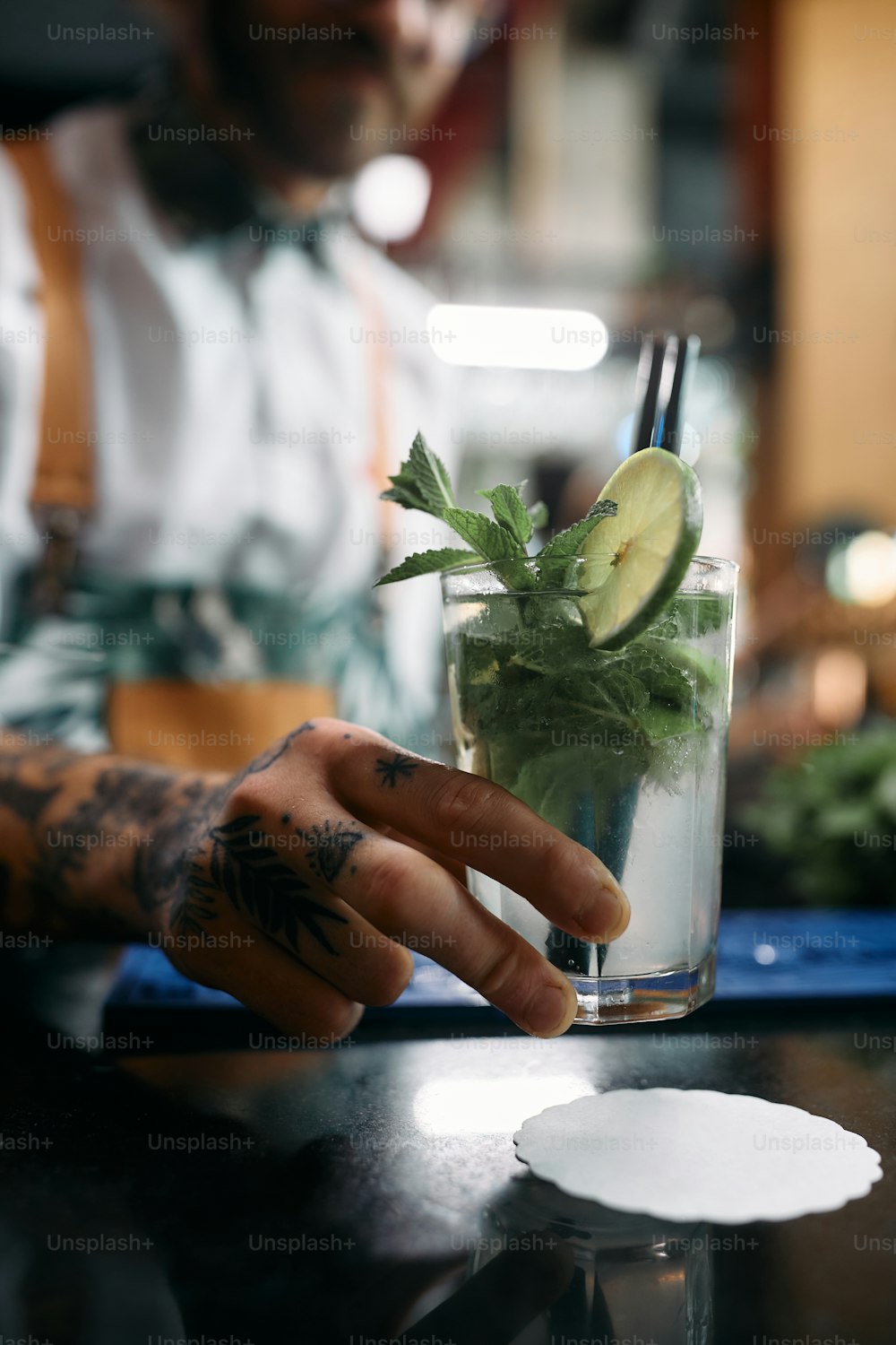 Close-up of bartender serving mojito cocktail in a pub.