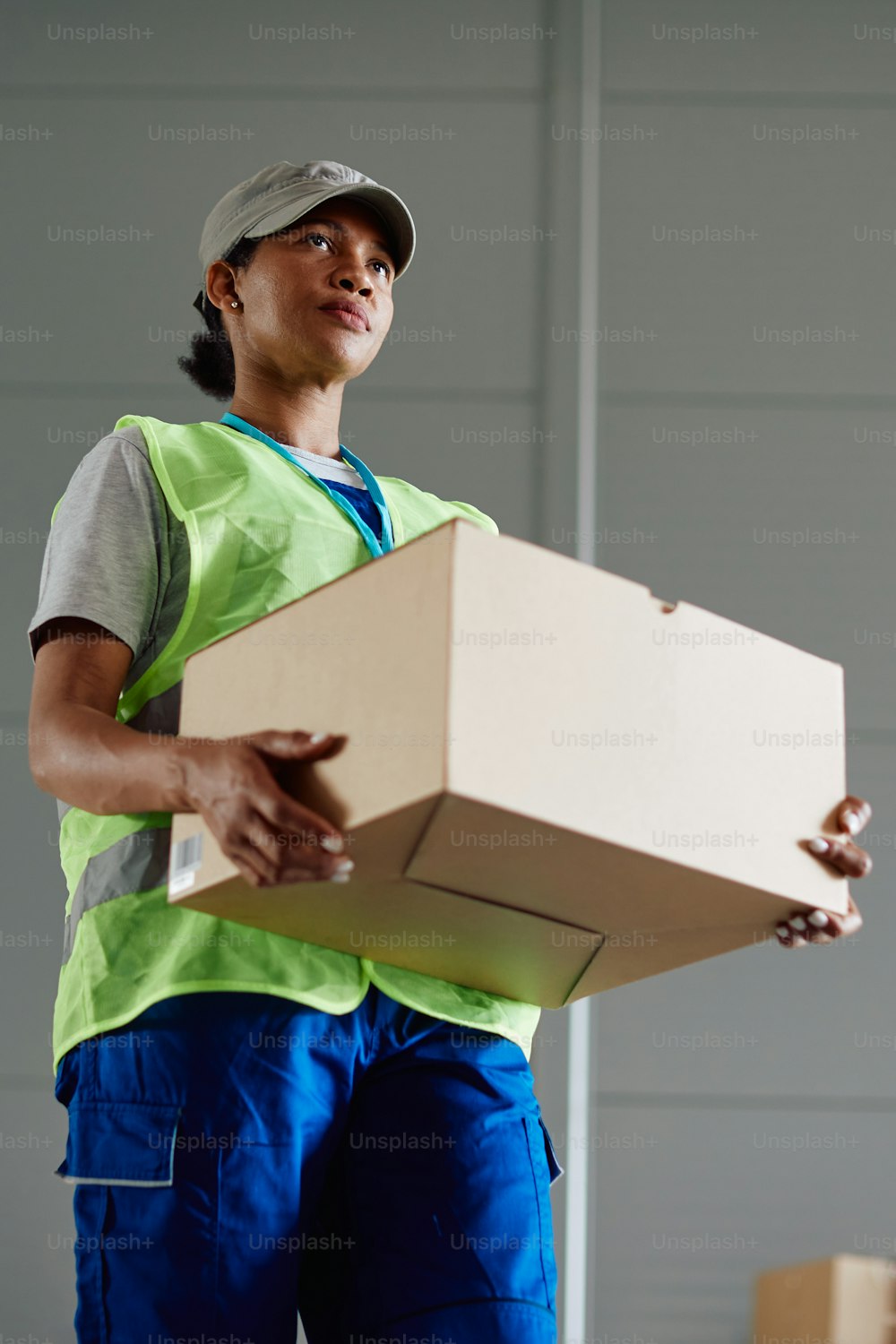 Visão de baixo ângulo da mulher afro-americana carregando o pacote enquanto trabalhava no armazém de distribuição.