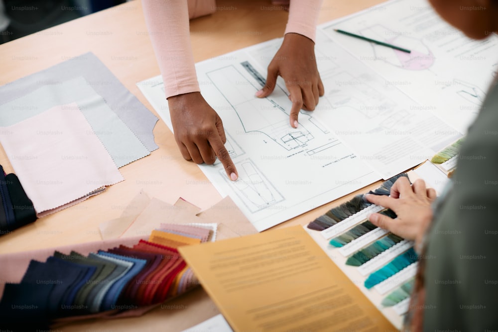 Close-up of designers cooperating while working on new clothing line in fashion design workshop.