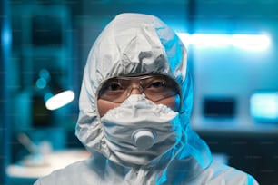 Chefe de jovem trabalhadora de laboratório asiática ou cientista em óculos de proteção, respirador e macacão