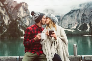 Retrato de una pareja romántica de adultos que visitan un lago alpino en Braies, Italia, en invierno. Turista enamorado bebiendo café caliente en las montañas. Pareja, pasión por los viajes y concepto de viaje.