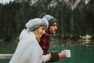 Portrait d’un couple romantique d’adultes visitant un lac alpin à Braies, en Italie, en hiver. Touriste amoureux buvant du café chaud dans les montagnes. Couple, envie de voyager et concept de voyage.