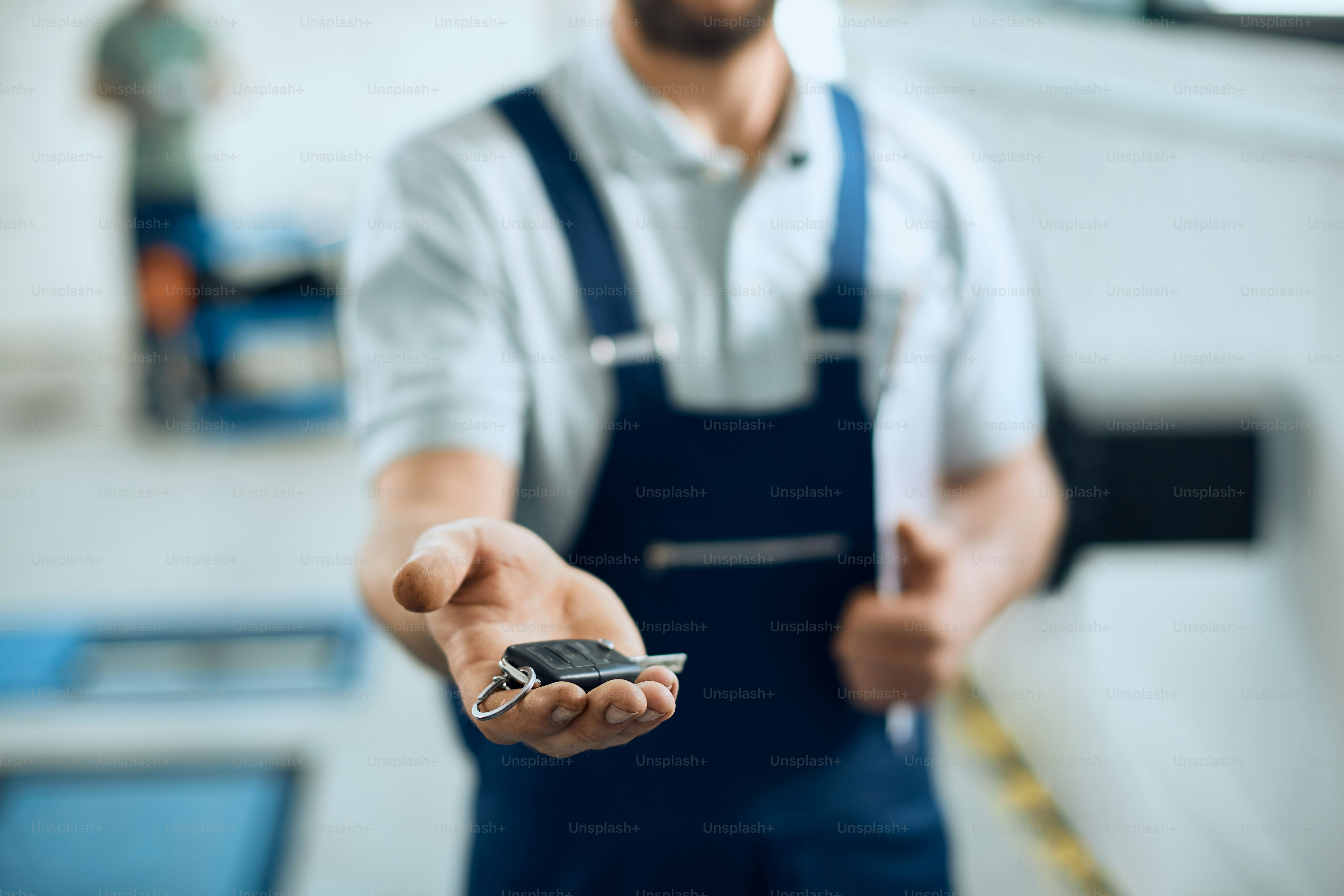 Close-up of mechanic giving car keys in auto repair workshop.