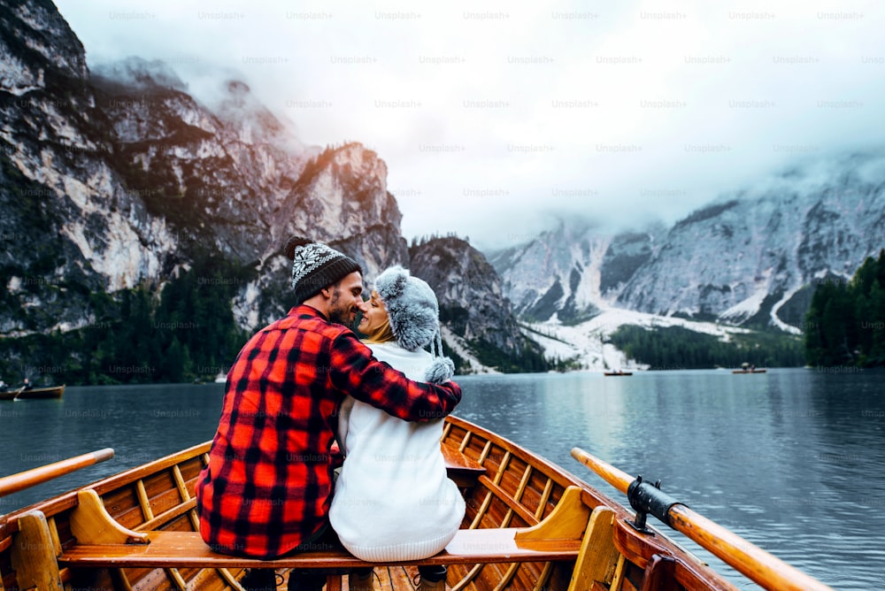 Braies 이탈리아의 고산 호수를 방문하는 보트에서 낭만적 인 커플. 사랑에 빠진 관광객은 가을 산에서 함께 사랑의 순간을 보냅니다. 여행, 커플, 방랑자에 대한 개념.