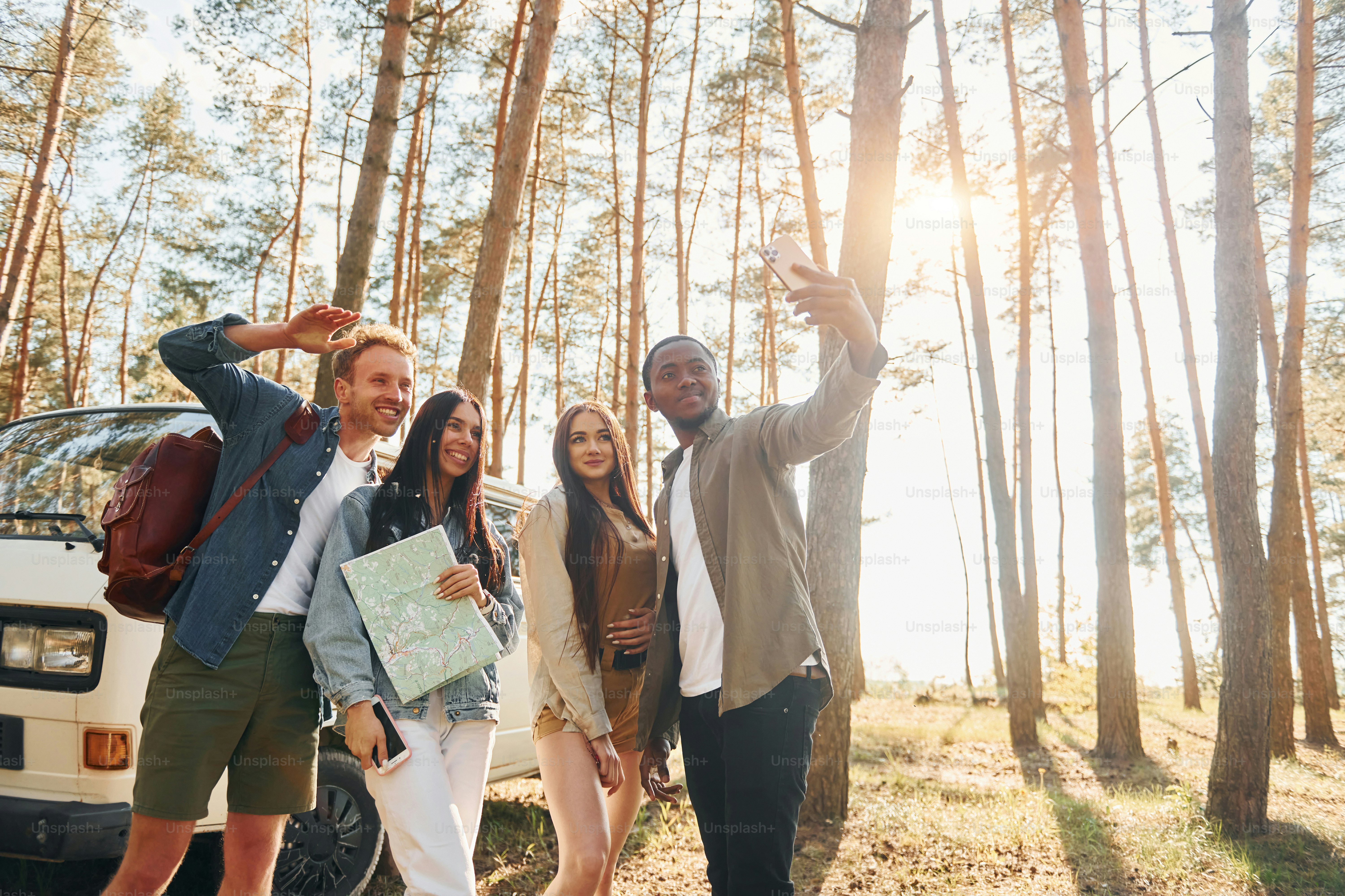 Fazendo selfie. Grupo de jovens está viajando juntos na floresta durante o dia.