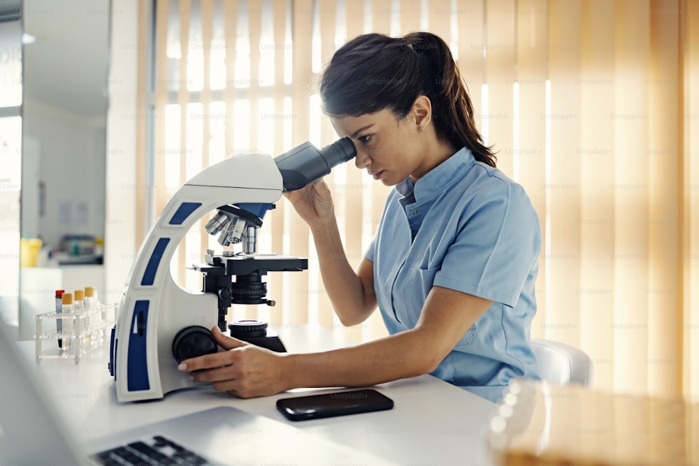 Un assistente di laboratorio in laboratorio che utilizza il microscopio per i test. Supporto medico, esami di laboratorio e assistenza medica.