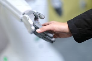Aperto de mão humano e robô, mãos em close-up, embaçado. Assistente mecânico humano. Sensibilidade tátil, inteligência artificial