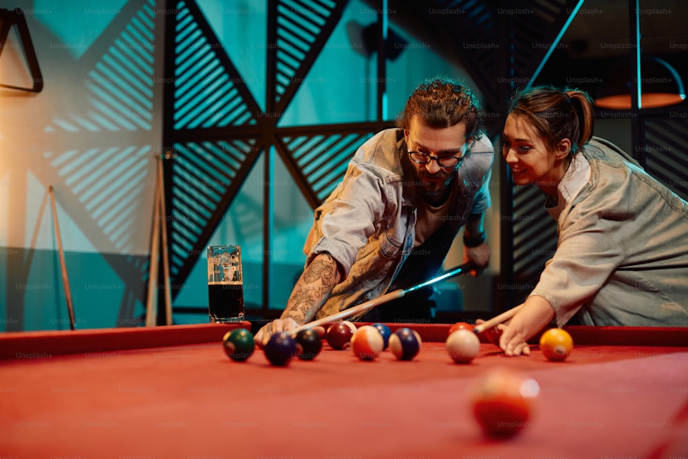 Young couple enjoying while playing billiard during their date in a pub.