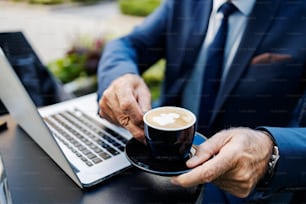 Fresh coffee held by a businessman. Close up of hands of a senior businessman holding fresh coffee.