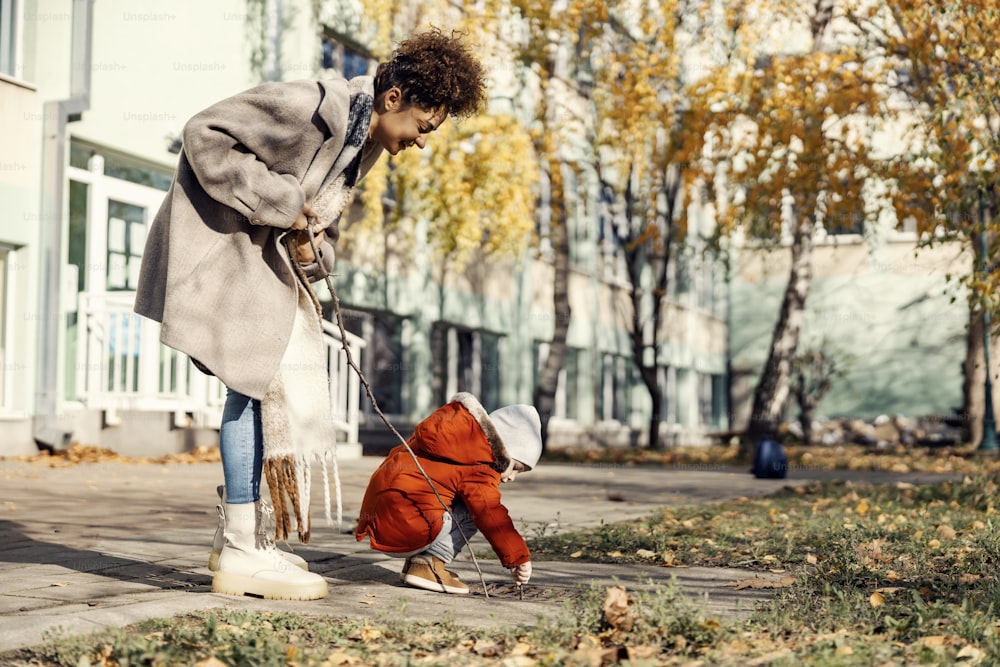 A little boy playing in schoolyard with his babysitter or nanny.