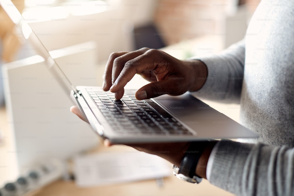Close-up de empresário afro-americano trabalhando em laptop no escritório.