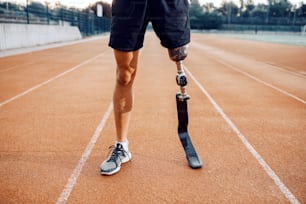 Sportler mit künstlichem Bein steht auf der Laufbahn im Stadion. Beine auf der Laufstrecke.