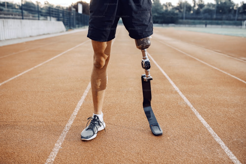 Sportif avec une jambe artificielle debout sur la piste de course au stade. Jambes sur piste de course.