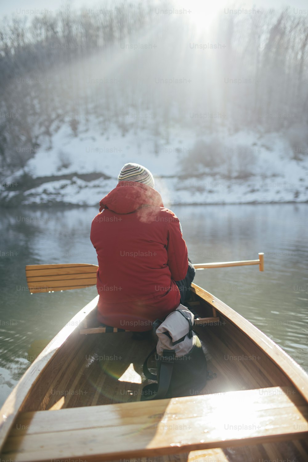Rear view of man paddling canoe on the winter sunny day.