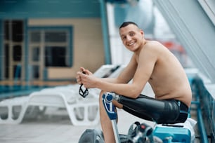 Happy athlete with artificial leg relaxing after swimming training and looking at camera.