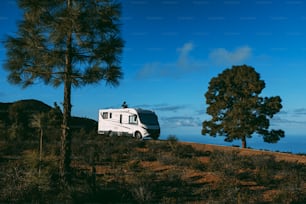 Modern camper van motorhome parked in the nature with sky view. Concept of people and travel vehicle vacation. Adventure vanlife lifestyle and nomadic life. Summer campsite holiday.