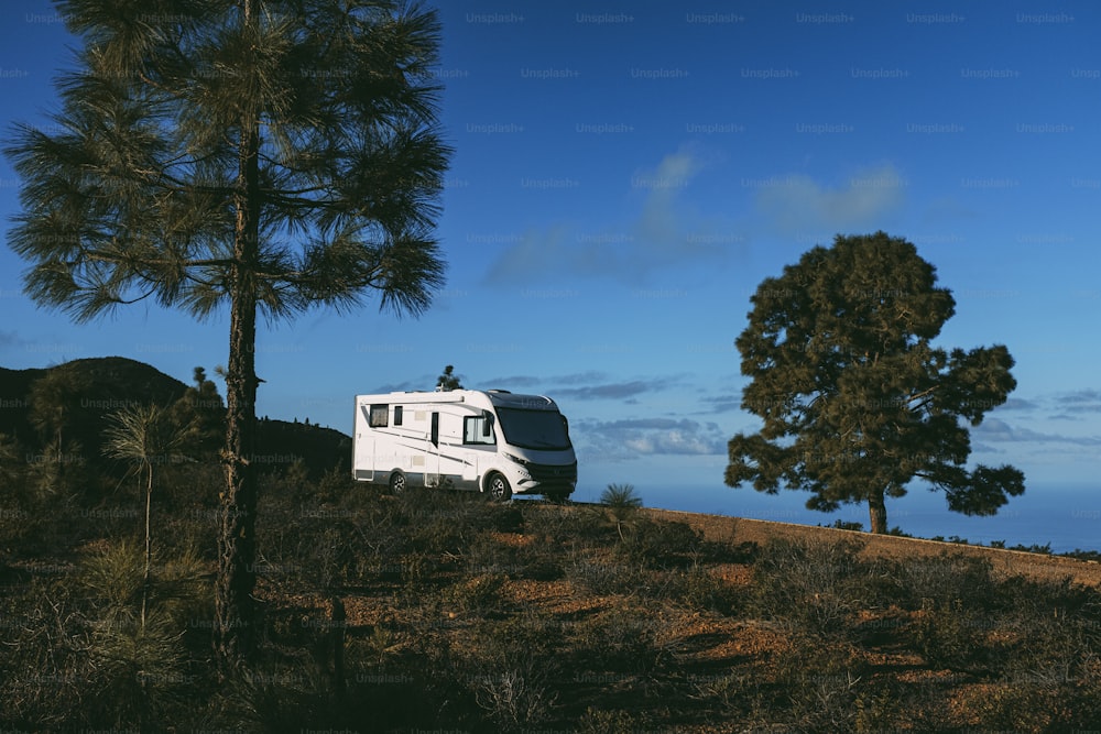 Modern camper van motorhome parked in the nature with sky view. Concept of people and travel vehicle vacation. Adventure vanlife lifestyle and nomadic life. Summer campsite holiday.