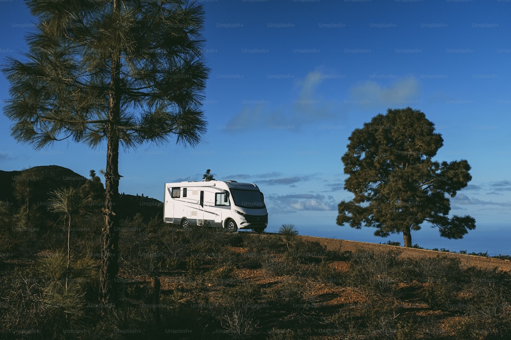 Modern camper van motorhome parked in the nature with sky view. Concept of people and travel vehicle vacation. Adventure vanlife lifestyle and nomadic life. Summer campsite holiday.