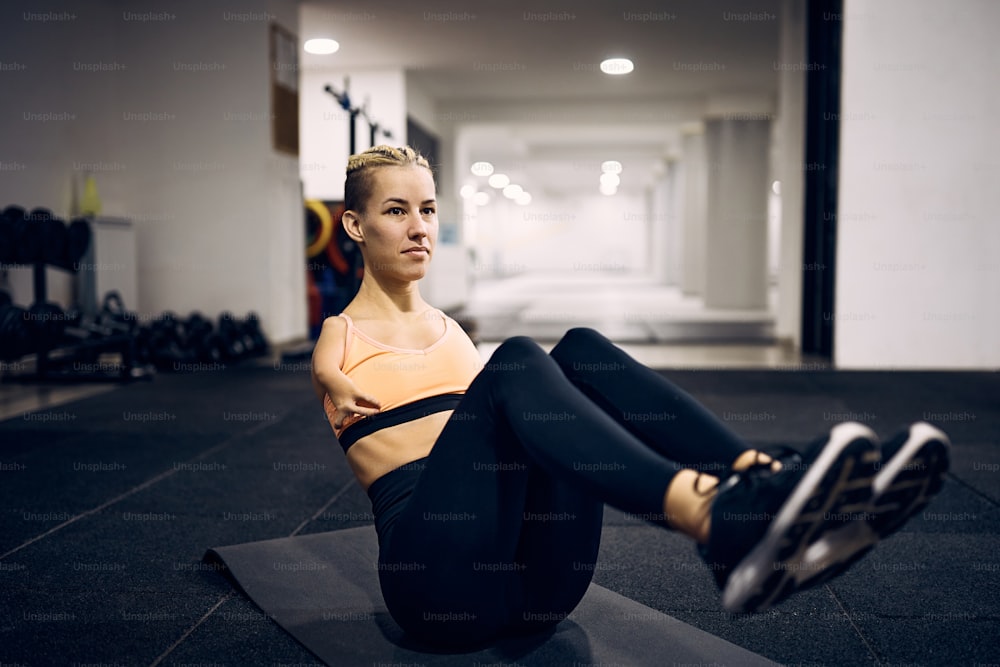 체육관에서 운동하는 동안 윗몸 일으키기를 하는 장애가 있는 운동 여성.