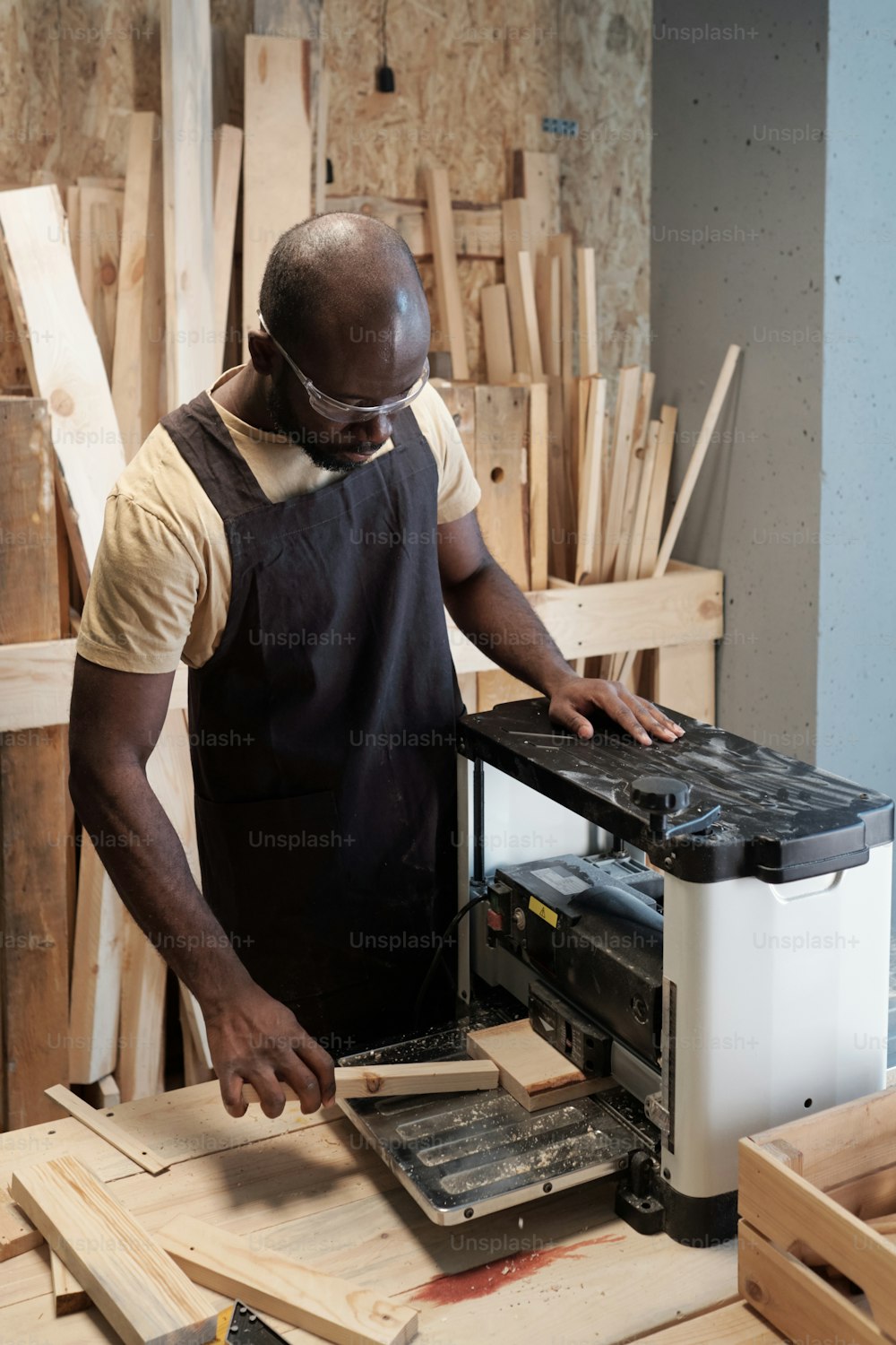 Vertical portrait of African-American man cutting wood in carpentry workshop