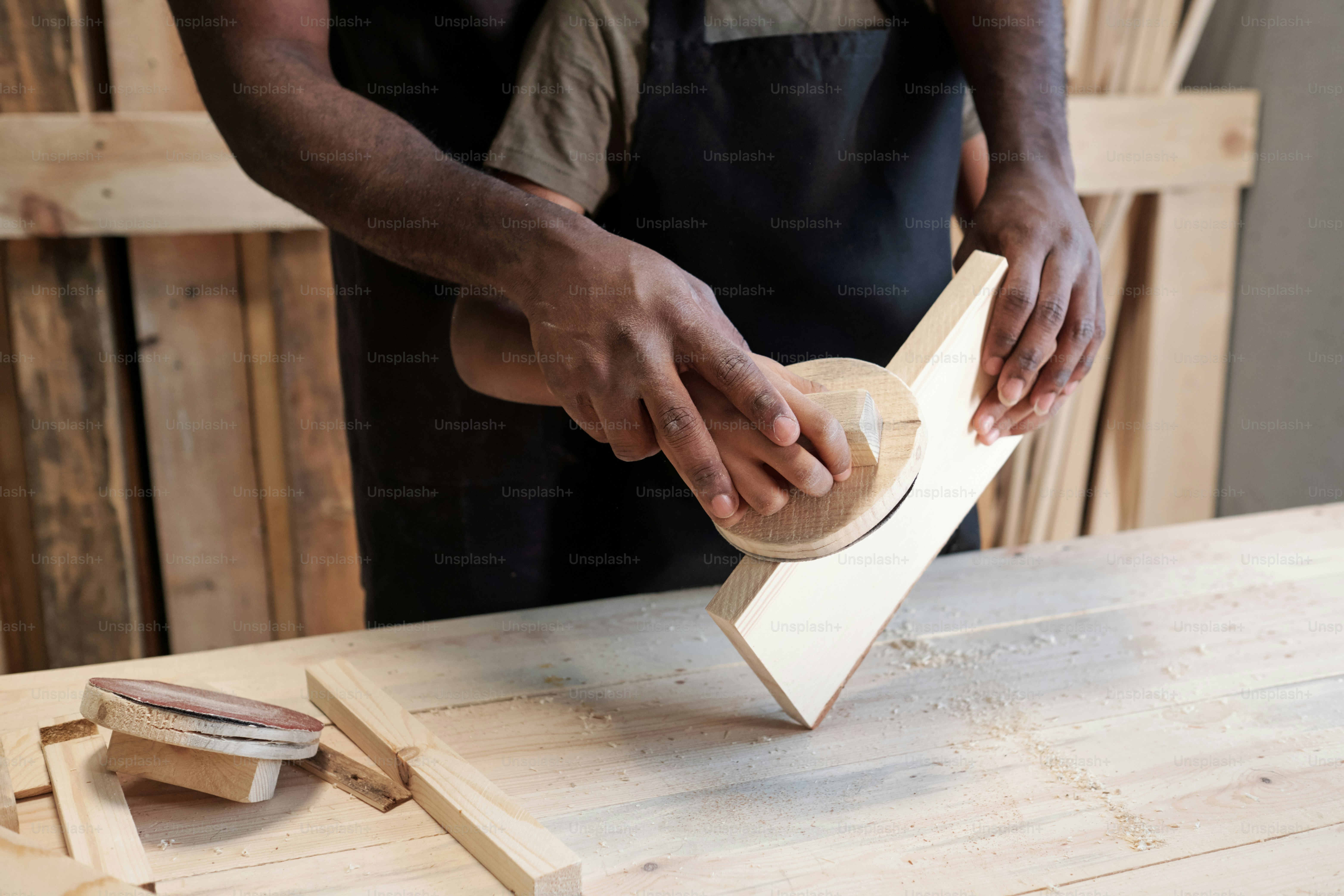 Close up of of caring African-American father teaching son in carpentry workshop, hands on piece of wood, copy space
