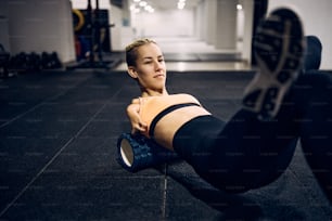 Motivated athlete with a disability using foam roller warming up for her sports training in a gym
